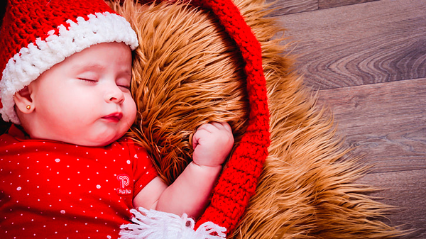 Criança dormindo com roupas vermelhas, tradicionais do Natal
